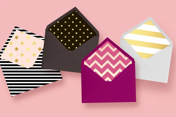 Colored envelopes, on a pink background. Chevron, polka dots,  gold stars, and gold stripes