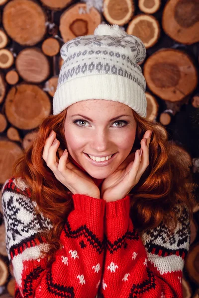 Attractive young woman in a winter fashion shot wearing a wool white cap, a red woolen sweater