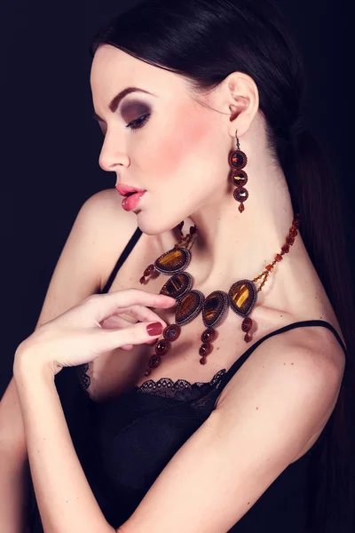 Beautiful woman with dark hair and evening makeup. Jewelry and Beauty. Fashion art photo