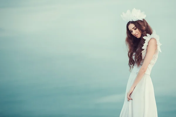 Beautiful bride posing on the coast with angelic dress