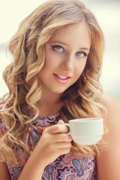 A lovely young girl with blond hair eating dessert and drinking