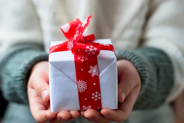 Gift box tied with a red ribbon in the hands