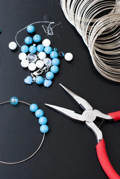 Turquoise and white beads, memory wire for bracelet, tools for creating fashion jewelry in the manufacturing process