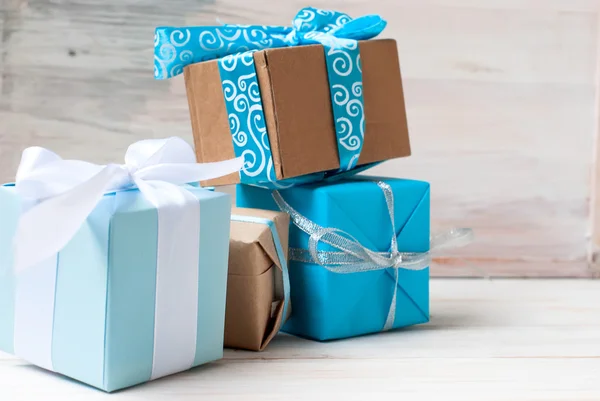 Boxes with gifts decorated with ribbons on a white wooden backgr