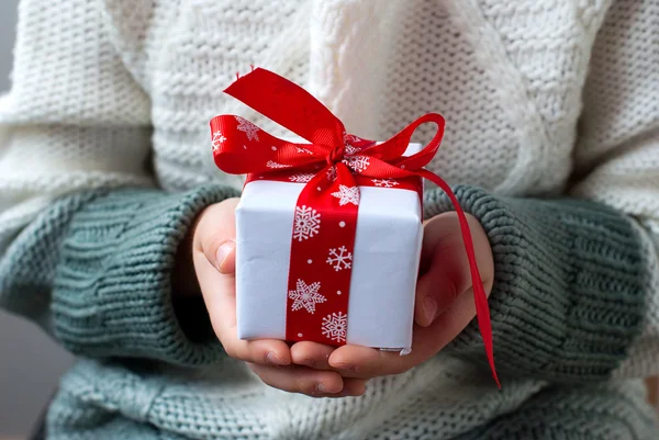 Gift box tied with a red ribbon in the hands