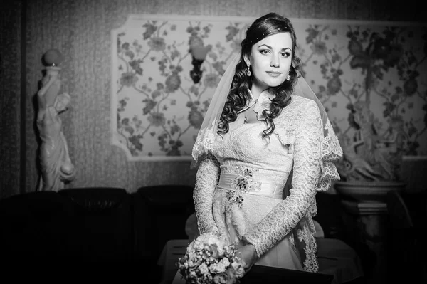 Gorgeous bride blonde in wedding dress on luxury interior with diamond jewelry posing at home and waiting for groom.