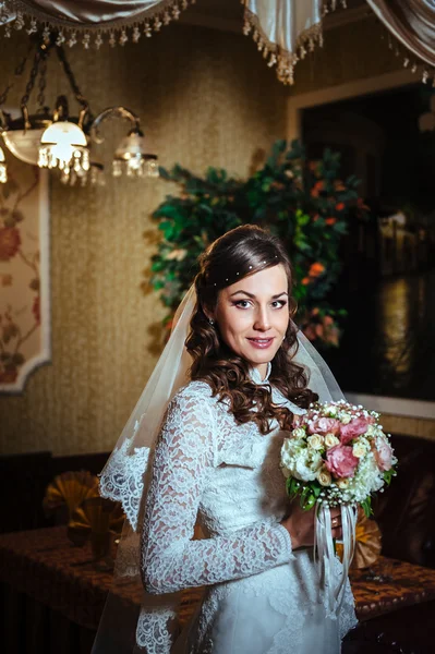 Gorgeous bride blonde in wedding dress on luxury interior with diamond jewelry posing at home and waiting for groom.