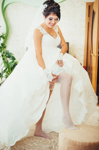 Bride putting a wedding garter on her leg