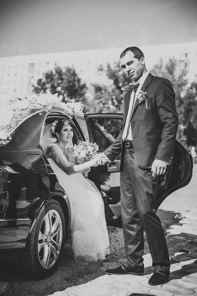 Happy groom helping his bride out of the wedding car.