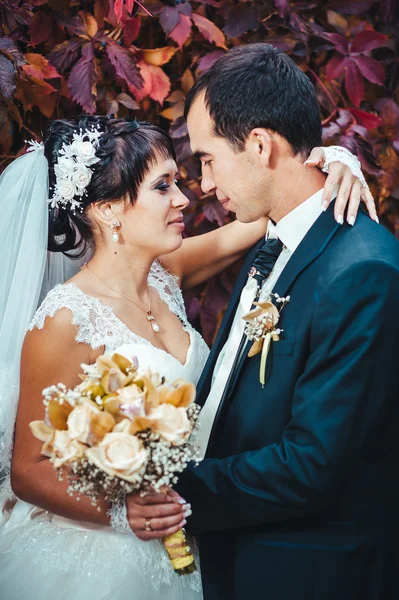 Young couple kissing in wedding gown. Bride holding bouquet of flowers