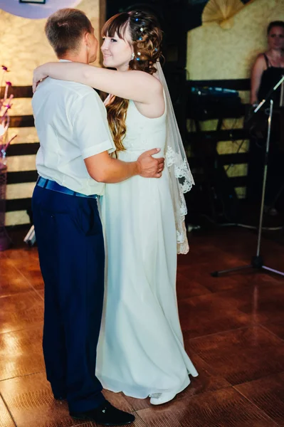 Wedding dance of young bride and groom in banqueting hall. Kiss, embrace