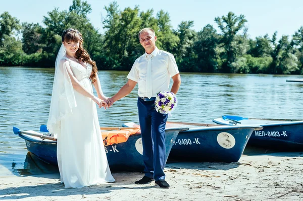 A wedding by the sea. Honeymoon. The bride and groom hugging on the shore of Lake. groom and bride hugging on a green lake. Groom and Bride in a park. wedding dress. Bridal wedding bouquet of flowers