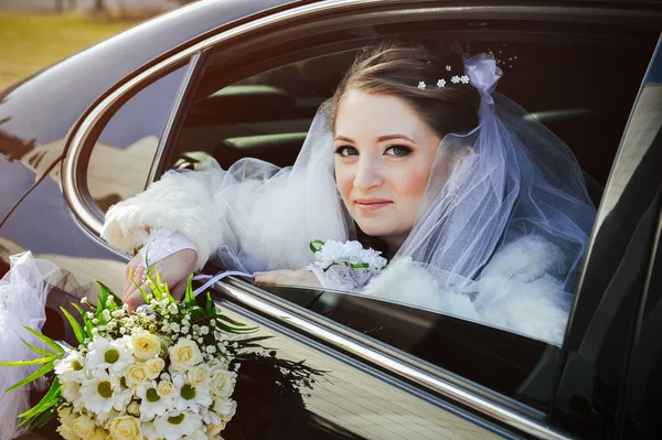 Close-up portrait of pretty shy bride in a car window