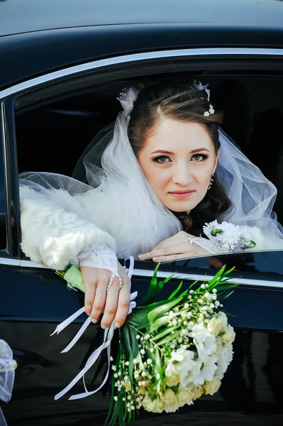 Close-up portrait of pretty shy bride in a car window