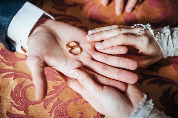 Wedding Couples hands on the table and rings, bridal bouquet flowers