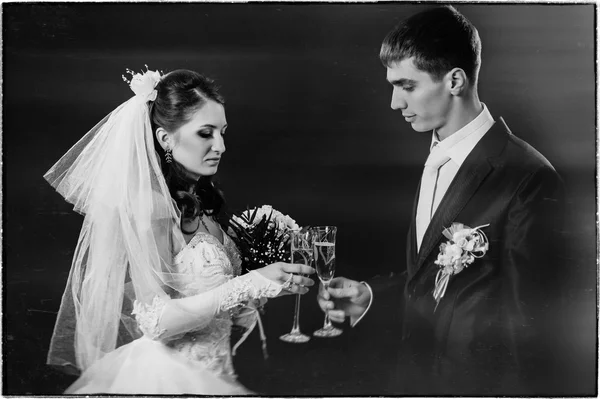 Wedding couple kissing and drinking champagne. Black background.