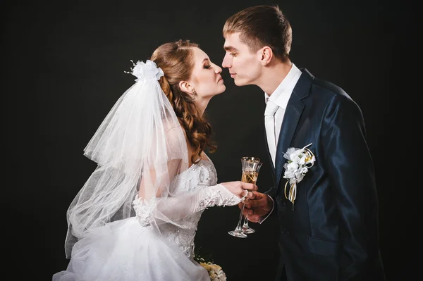 Wedding couple kissing and drinking champagne. Black background.