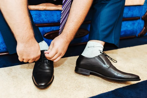 Best man getting ready for a special day. groom putting his wedding shoes.