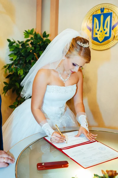 Wedding ceremony. Registry office. A newly-married couple signs the marriage document.Young couple signing wedding documents