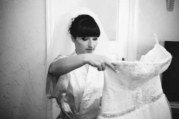 Beautiful bride getting ready in white wedding dress with hairstyle and bright makeup. Happy sexy girl waiting for groom. Romantic lady in bridal dress have final preparation for wedding.