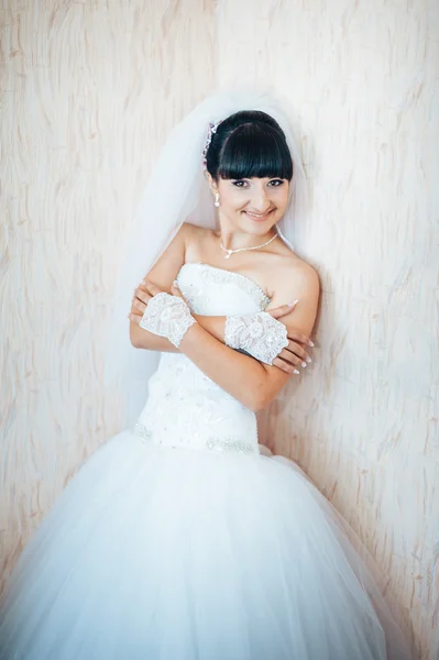 Beautiful bride getting ready in white wedding dress with hairstyle and bright makeup. Happy sexy girl waiting for groom. Romantic lady in bridal dress have final preparation for wedding.