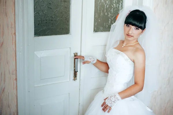 Beautiful bride getting ready in white wedding dress with hairstyle and bright makeup. Happy sexy girl waiting for groom. Romantic lady in bridal dress have final preparation for wedding.