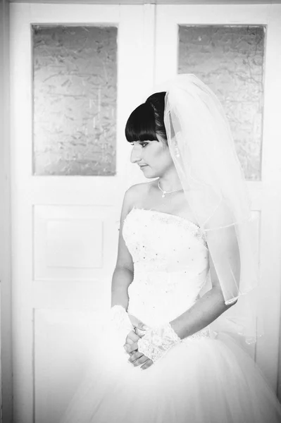 Beautiful bride getting ready in white wedding dress with hairstyle and bright makeup. Happy sexy girl waiting for groom. Romantic lady in bridal dress have final preparation for wedding.