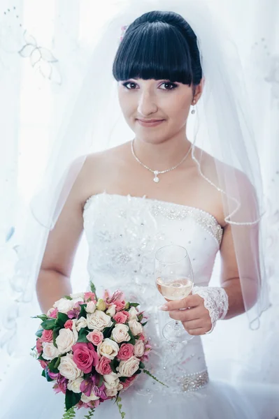 Beautiful bride getting ready in white wedding dress with hairstyle and bright makeup. Happy sexy girl waiting for groom. Romantic lady in bridal dress have final preparation for wedding.