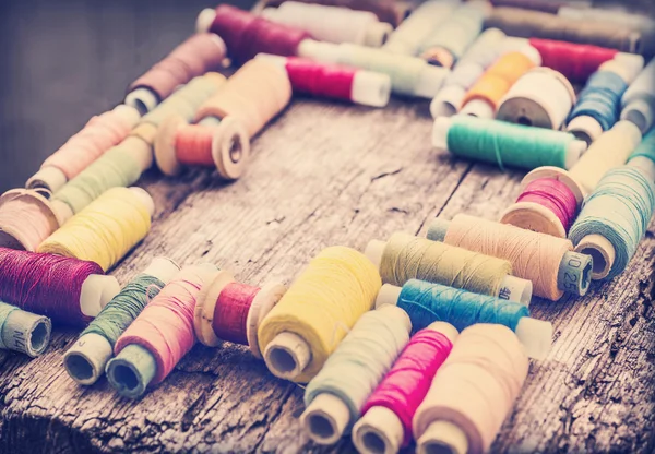 Bobbins with colorful threads on wooden table