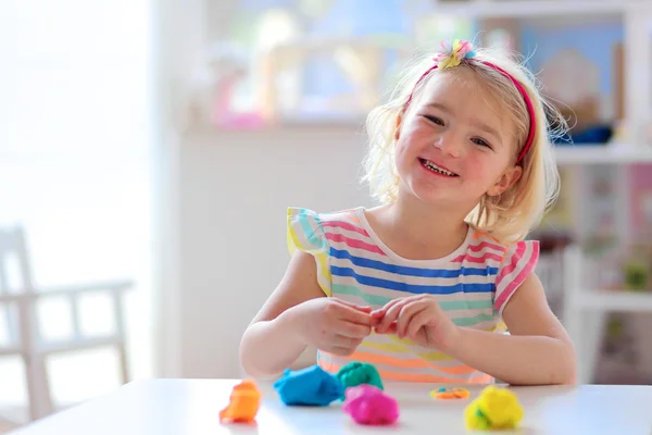 Happy preschooler girl playing with plasticine