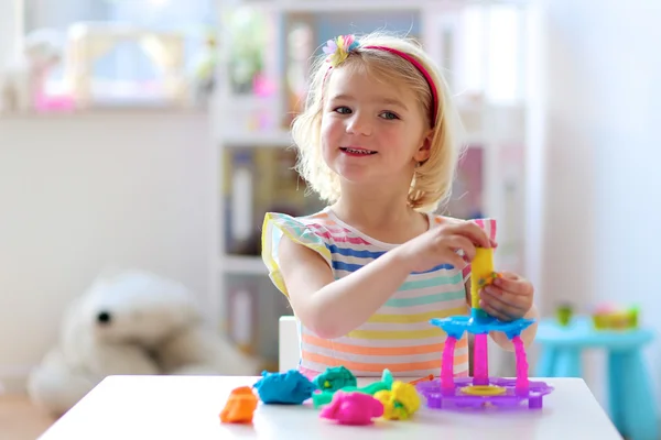 Happy preschooler girl playing with plasticine