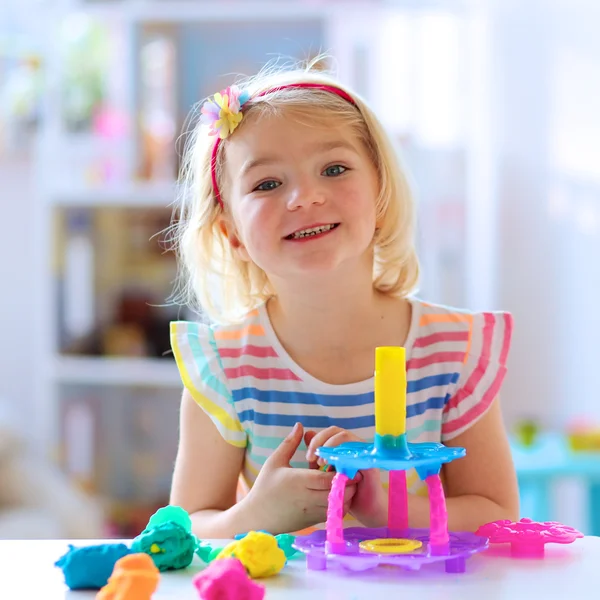 Happy preschooler girl playing with plasticine