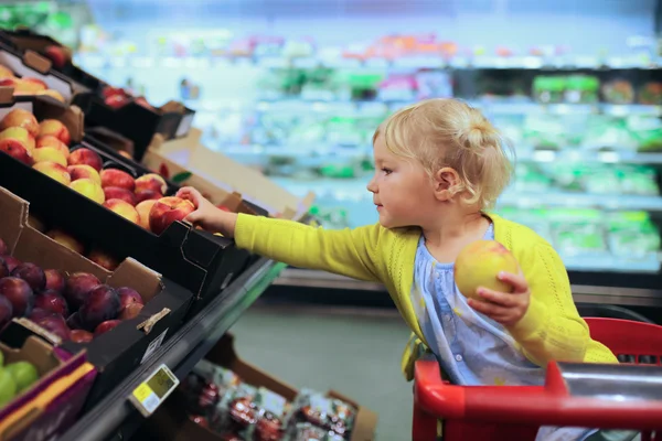 Cute little girl buying fruits in supermarket