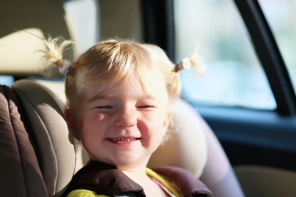 Funny little girl in car seat with safety belt