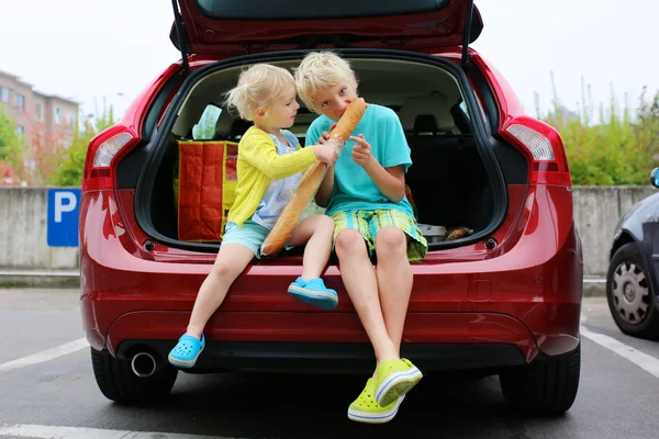 Brother and sister sitting in trunk after shopping