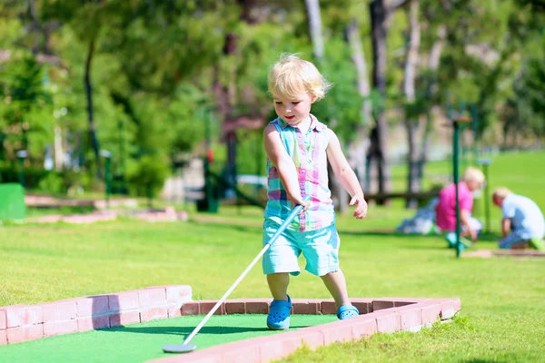 Group of kids playing mini golf outdoors