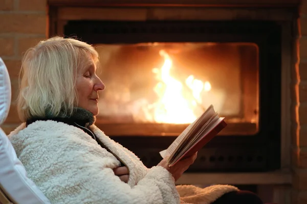 Senior lady relaxing at home by fireplace