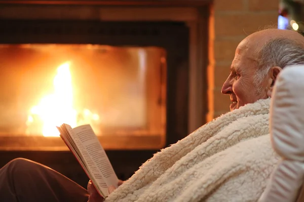 Senior man relaxing at home by fireplace
