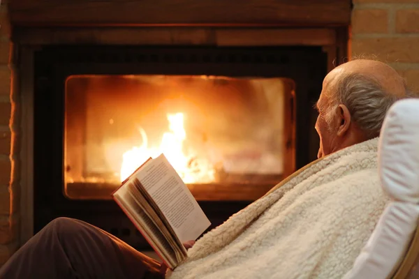 Senior man relaxing at home by fireplace