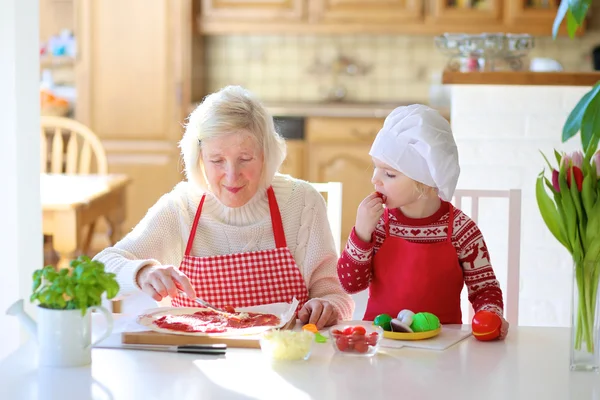 Grandma with granddaughter preparing pizza