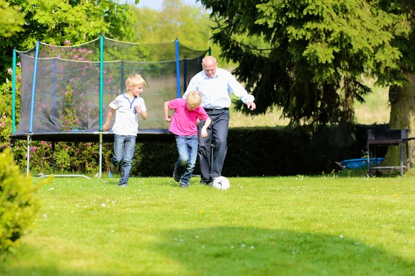 Grandfather with grandsons playing soccer in the garden