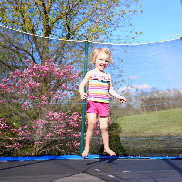 Cute toddler girl jumping on trampoline