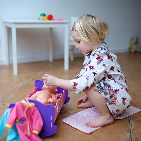 Toddler girl playing with dolls indoors