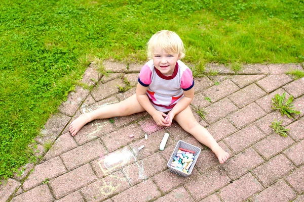 Preschooler girl drawing with chalk outdoors