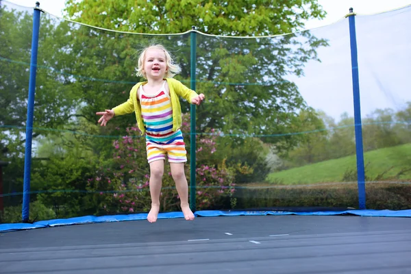 Preschooler girl jumping on trampoline