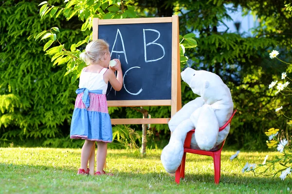 Toddler girl playing teacher with her toys