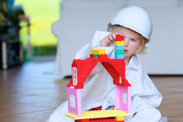 Toddler girl wearing safety helmet playing with building blocks