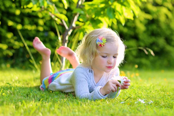 Little kid playing in garden lying in grass