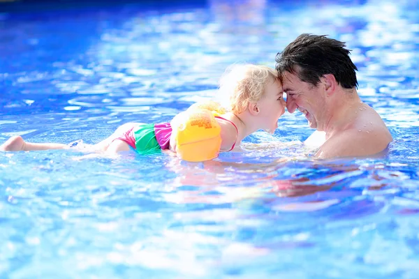 Father and daughter swimming in summer pool