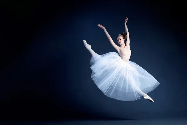 Young ballerina with a perfect body is dancing in the photostudio in different dresses